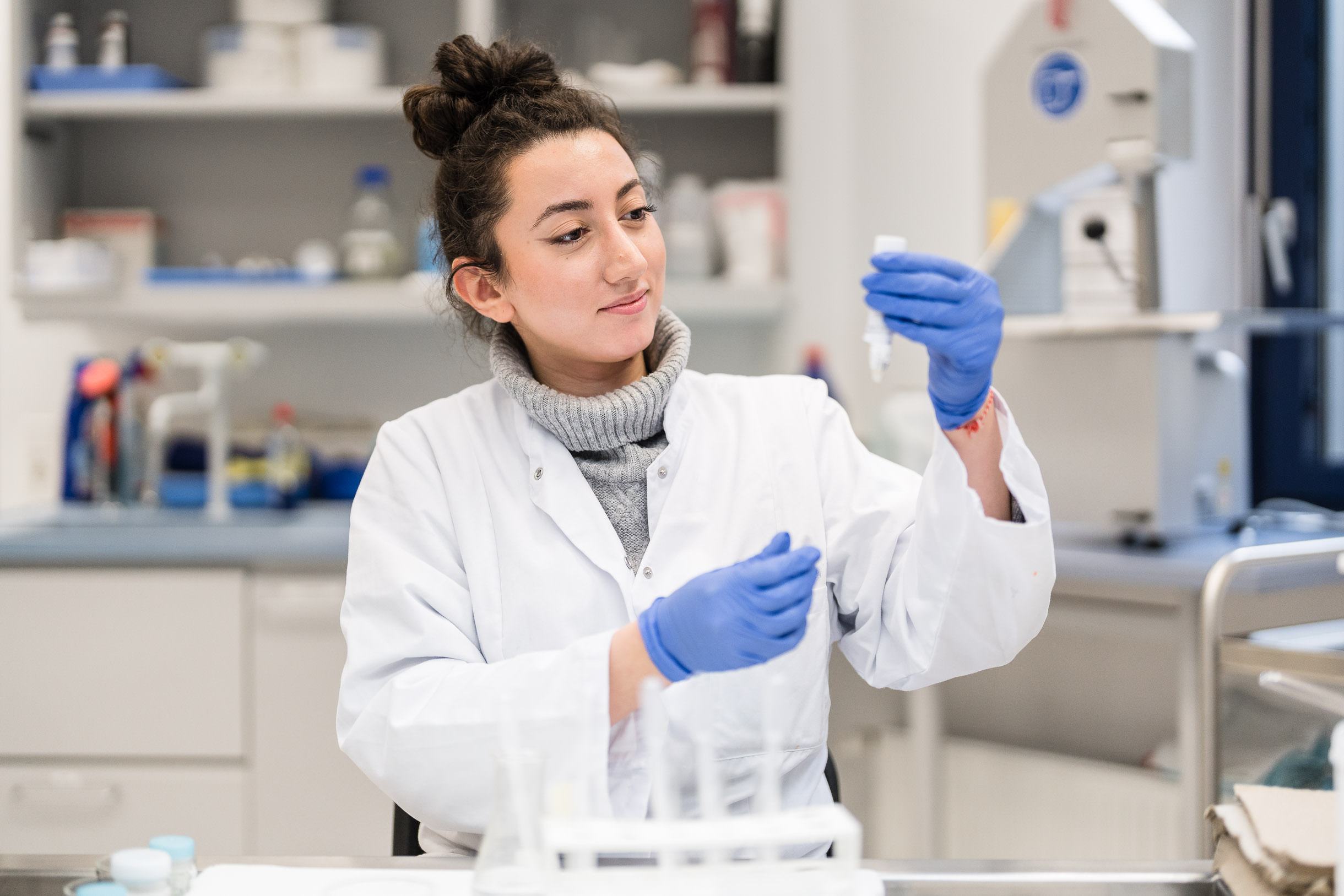 Businessfotos im Labor der Pathologie in Paderborn, eine Mitarbeiterin begutachtet eine Pipette mit Flüssigkeit im Unternehmen.